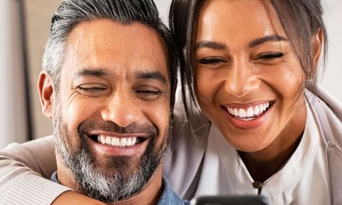 a man and woman smiling while looking at a phone