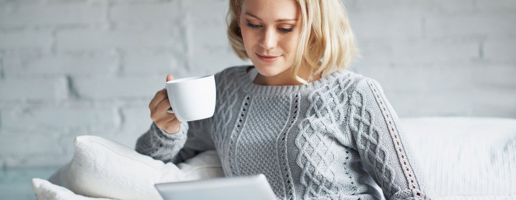 a woman holding a cup and a tablet